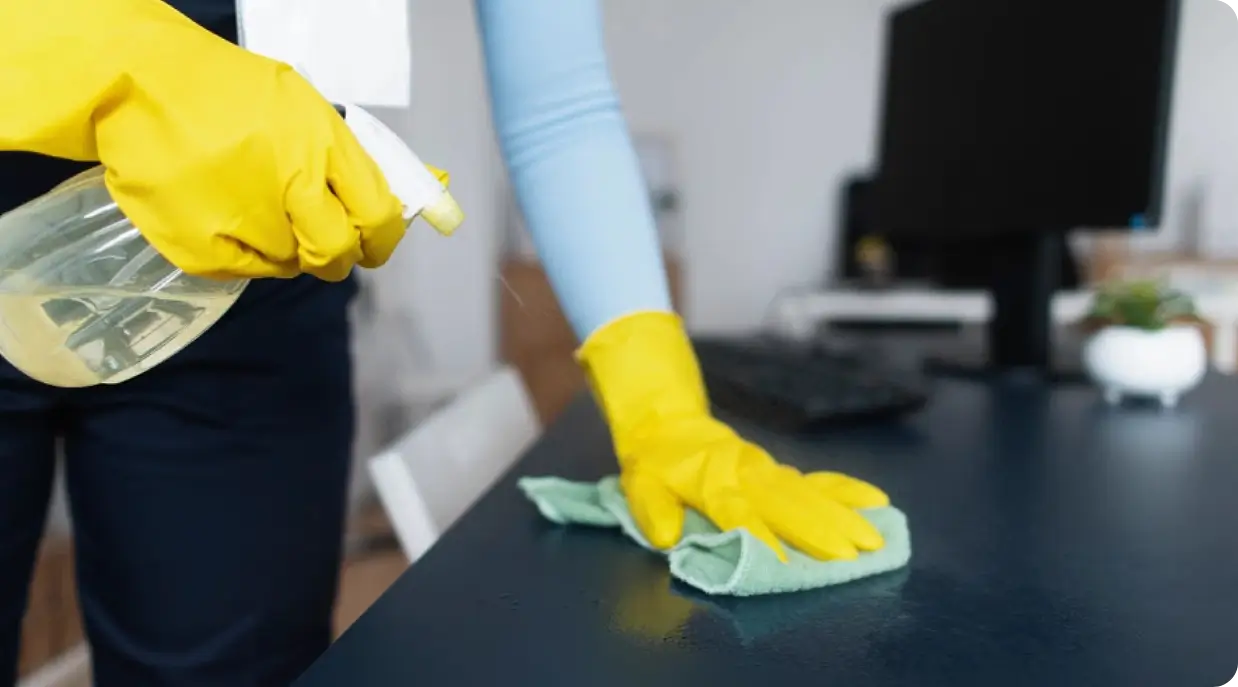 A person wearing gloves and cleaning the table