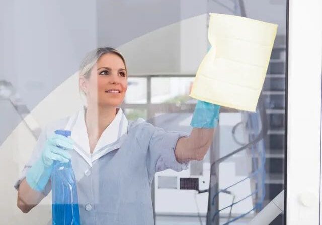 A woman in blue gloves holding papers and a glass