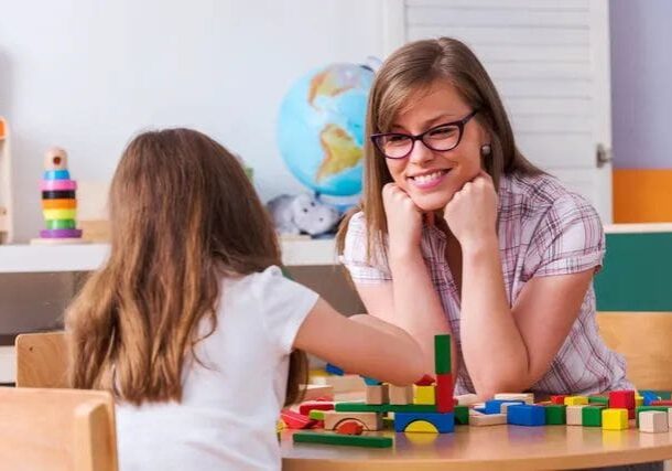 A woman and girl sitting at a table with blocks.